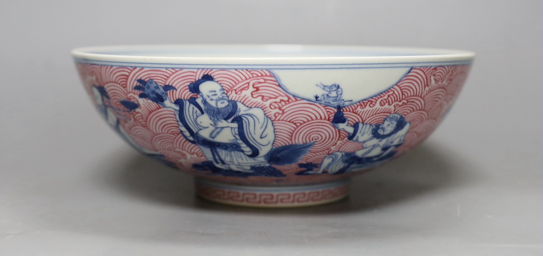 A Chinese underglaze blue and puce enamelled 'eight immortals' bowl, 22cm diameter